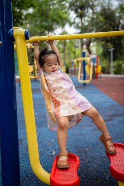 Sevimli küçük kız oyun parkına tırmanırken eğleniyor.