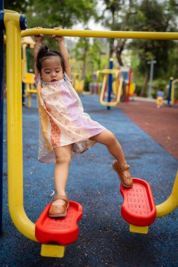 Sevimli küçük kız oyun parkına tırmanırken eğleniyor.