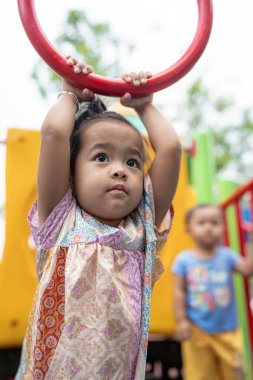 Sevimli küçük kız oyun parkına tırmanırken eğleniyor.
