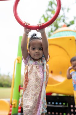Sevimli küçük kız oyun parkına tırmanırken eğleniyor.