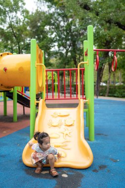 Sevimli küçük kız oyun parkına tırmanırken eğleniyor.