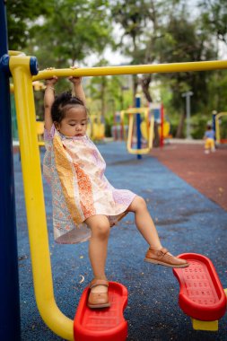Sevimli küçük kız oyun parkına tırmanırken eğleniyor.