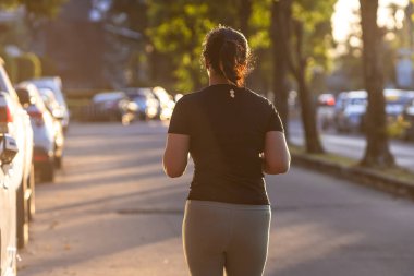Spor Asyalı kadın şehri, gün doğarken yolda koşuyor. Sağlıklı bir yaşam tarzı.