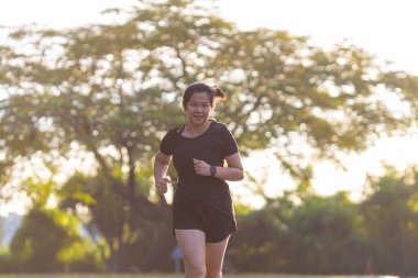 Spor Asyalı kadın şehri, gün doğarken yolda koşuyor. Sağlıklı bir yaşam tarzı.