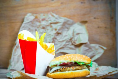 Lezzetli hamburger ve kızarmış patates ahşap arka plan üzerinde