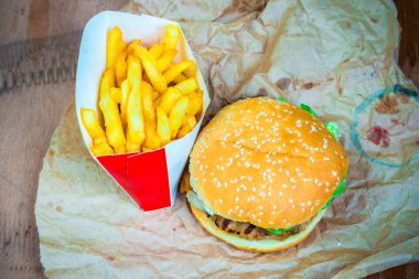 Lezzetli hamburger ve kızarmış patates ahşap arka plan üzerinde