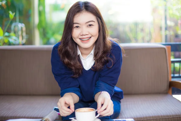 Attractive young woman sitting on sofa drinking coffee — Stock Photo, Image