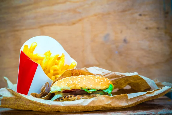 Вкусный гамбургер и картофель фри на деревянном фоне — стоковое фото