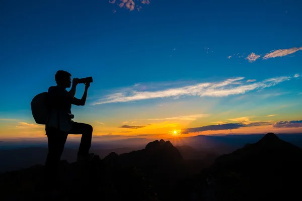 Fotógrafo hombre en la montaña alcanza el sol — Foto de Stock