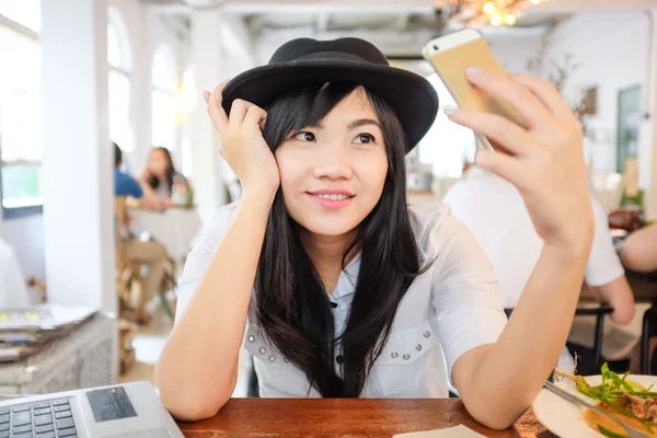 Young asian woman sitting at cafe drinking coffee and taking selfportrait, Beautiful girl sitting in a coffee house