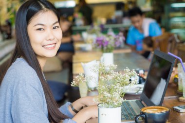Dizüstü bilgisayarda çalışan latte sanat kafede dizüstü kullanarak içme kadın.