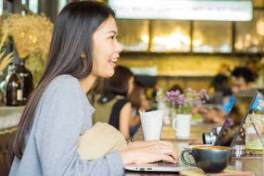 Asyalı kadın dizüstü latte sanat kahve ile kullanma