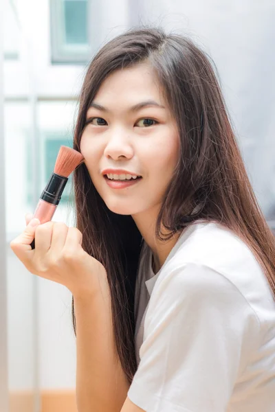 Young asian woman applying cosmetic paint brush — Stock Photo, Image