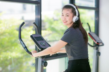 Asyalı kadın üzerinde çapraz bir eğitmen, kadın spor salonunda egzersiz fitness kulübünde eğitim