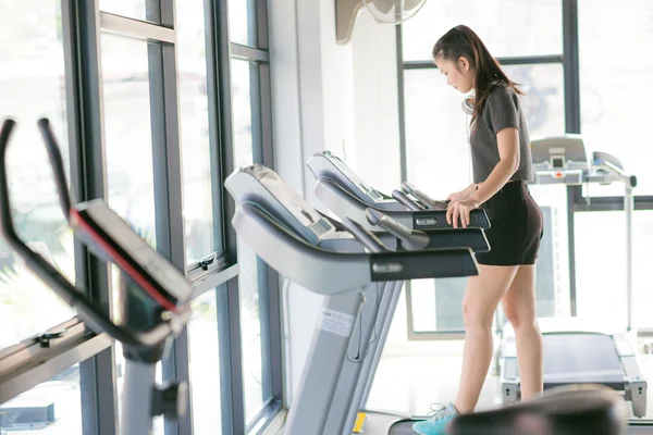 Mujer asiática haciendo ejercicio en el gimnasio en un cross trainer — Foto de Stock