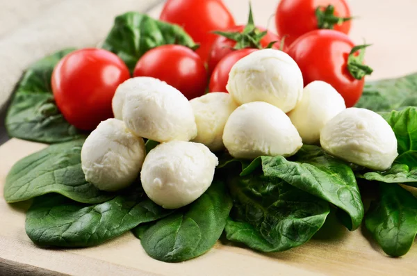 Mozzarella cheese balls, ripe cherry tomatoes and greens on the — Stock Photo, Image