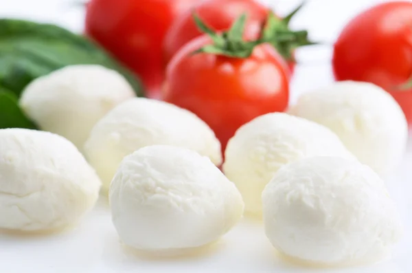 Mozzarella cheese balls and a ripe cherry tomatoes and greens on — Stock Photo, Image