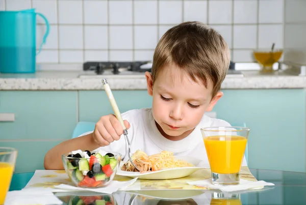 Menino comendo na mesa, olhando para o prato horizontal — Fotografia de Stock