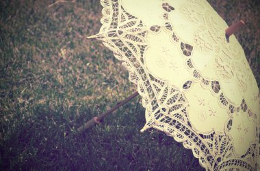 Lacy parasol on the grass close up. tinted vintage clipart