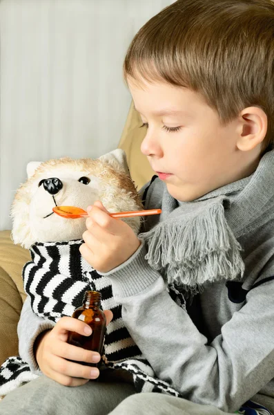 Liten pojke feeds läkemedel sirap leksak hund — Stockfoto