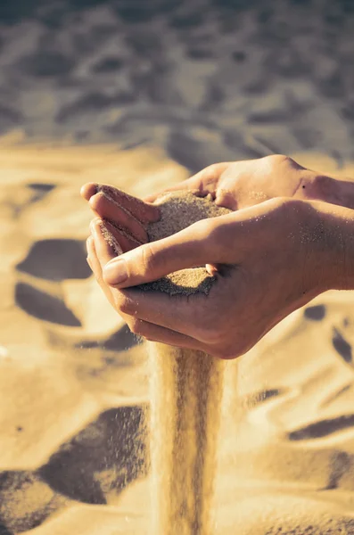 Areia imagem matizado derrama fora das mãos femininas — Fotografia de Stock