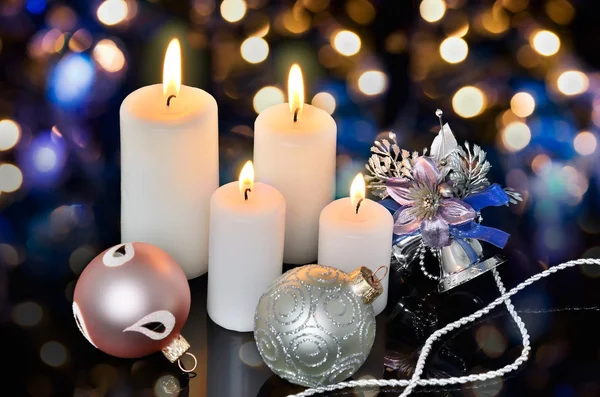 Fyra vita tända ljus och juldekorationer på en bokeh — Stockfoto