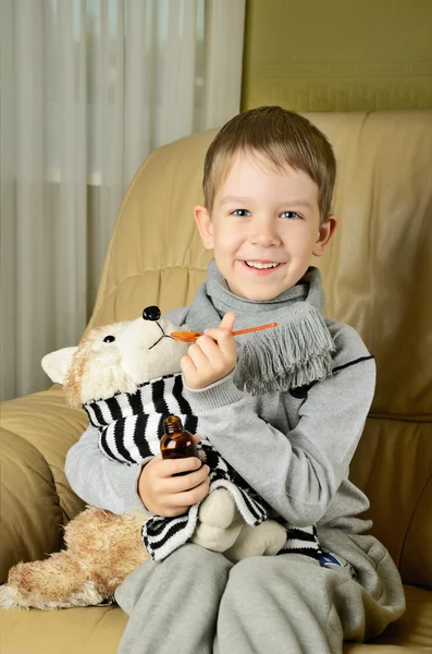 Маленький мальчик кормит лечебным сиропом игрушечную собаку и глядя на пришел — стоковое фото
