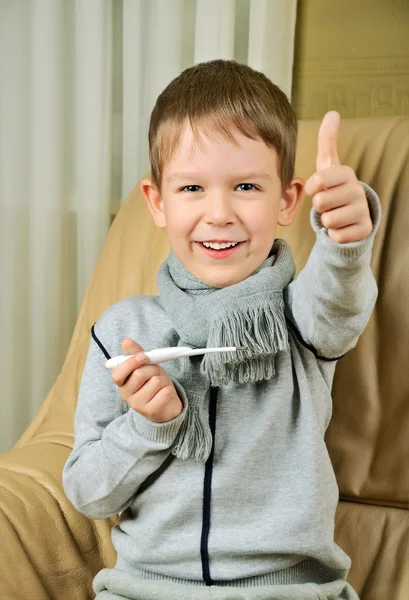 Laughing boy holding a thermometer and shows thumb — Stock Photo, Image