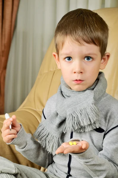 Junge hält Thermometer und Tabletten senkrecht — Stockfoto