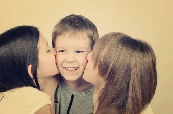 Tinted image two teens girls kissing little laughing boy — Stock Photo, Image