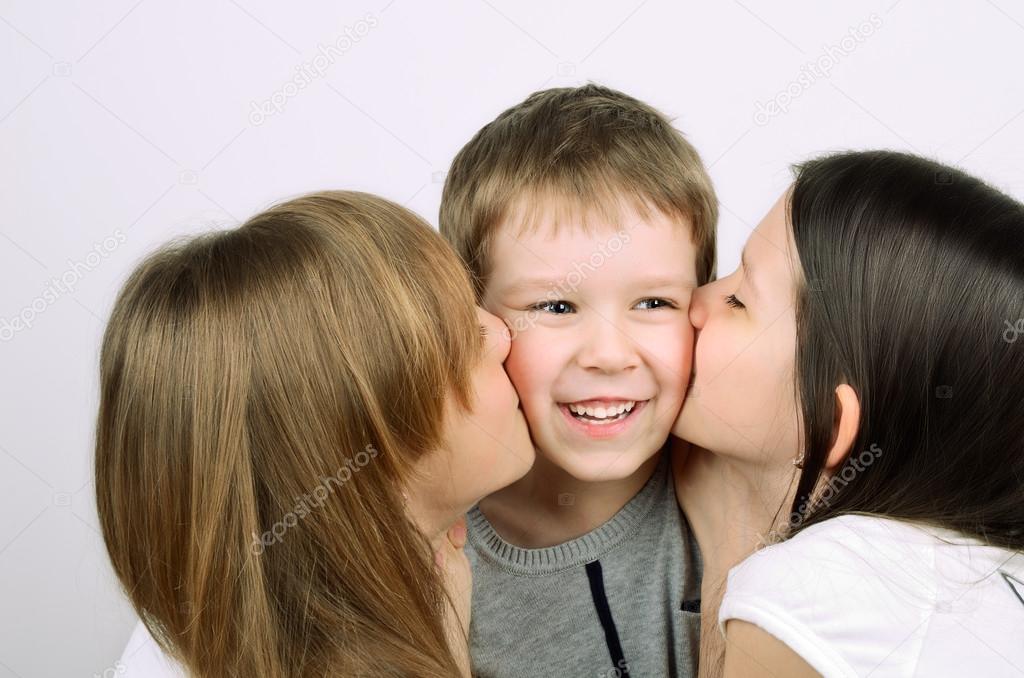 two teens girls kissing little laughing boy