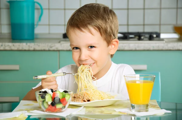 Skrattande pojken äta spaghetti och hålla gaffeln — Stockfoto