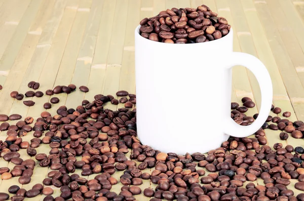Tasse blanche avec des grains de café est sur une table en bois. image teintée — Photo