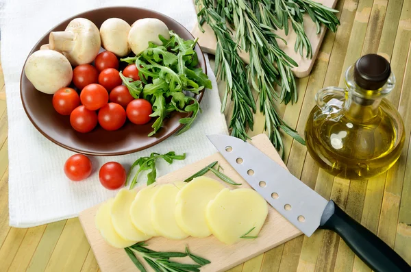 Cheese, tomatoes and herbs on a kitchen table top view — Stock Photo, Image