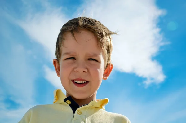 Little boy looks down on blue sky background horizontal — Stock Photo, Image