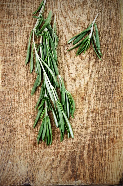 Two sprigs of rosemary on a wooden board top view — Stock Photo, Image