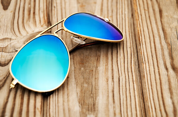 blue mirrored sunglasses on the wooden background close up
