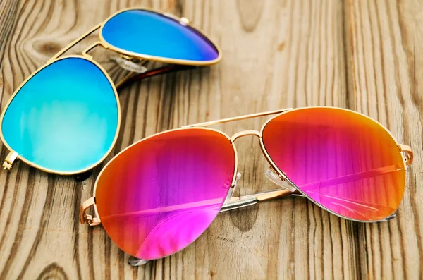 Two colored sunglasses on the wooden background — Stock Photo, Image