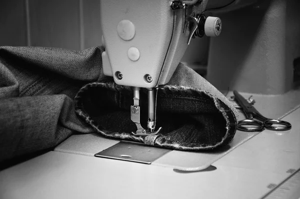 Machine à coudre et jeans en atelier de couture. monochrome — Photo