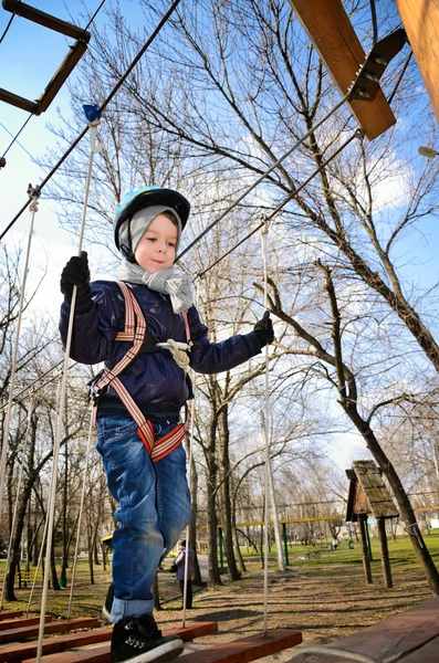 Boy going on suspension bridge and looking down. vertical — Stock Photo, Image