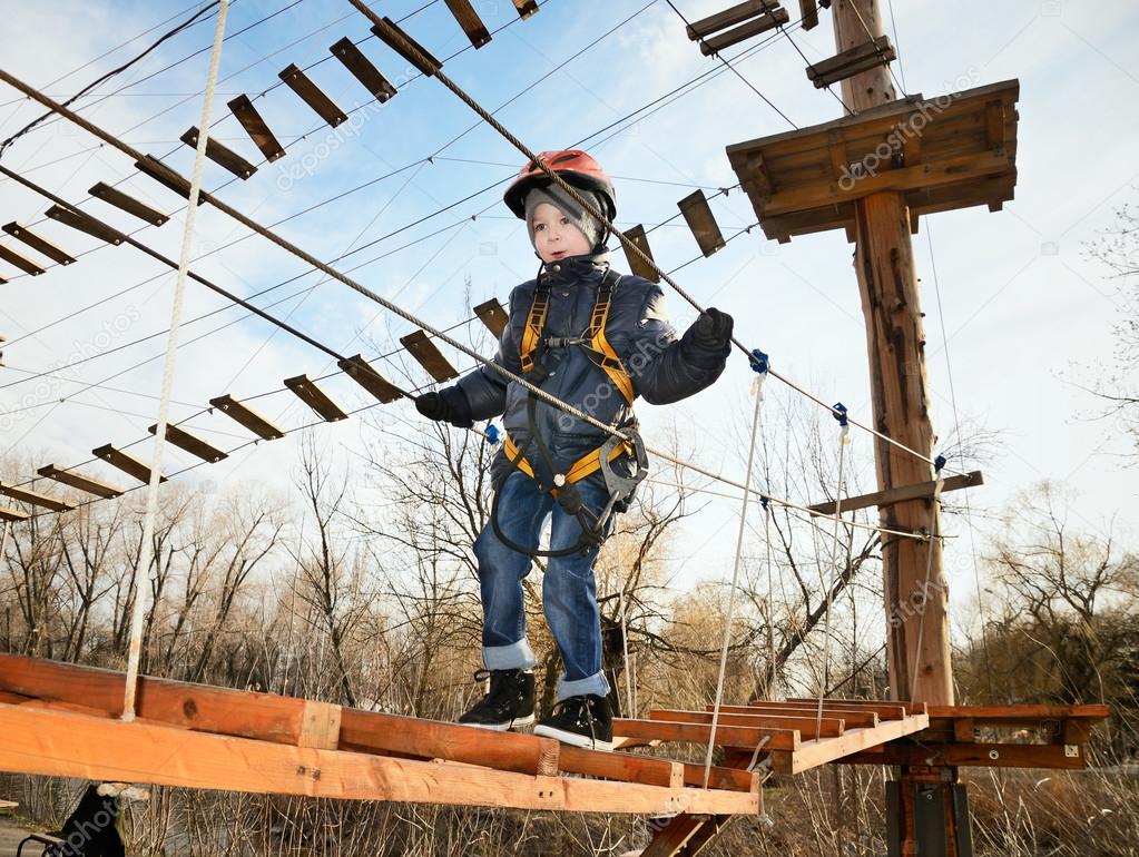 Little boy going on suspension bridge in the equipment and looki