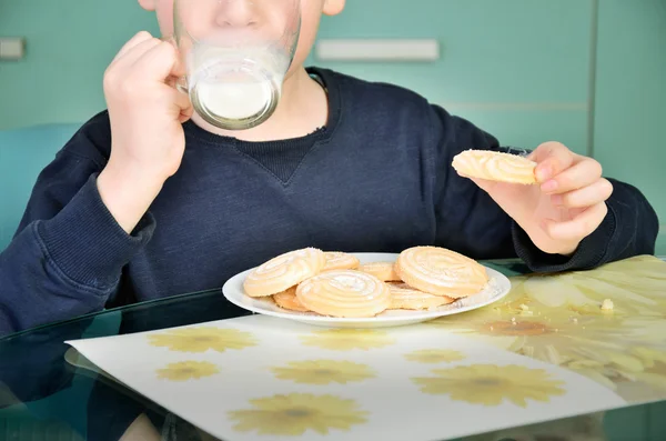 Little boy drinking milk, sitting at the dinner table. biscuits — Stock Photo, Image