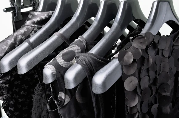 Abbigliamento nero delle donne appeso all'orizzonte appendiabiti in plastica nera — Foto Stock