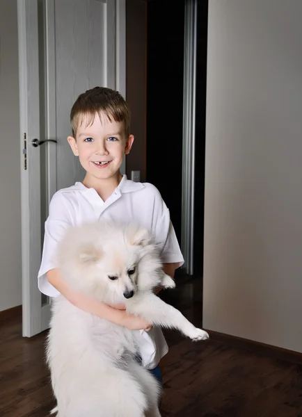 Sorridente bambino 6-7 anni che tiene il cane al coperto — Foto Stock