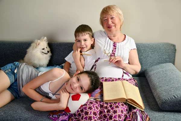 Grandma with grandchildren smiling sitting on the couch — Stock Photo, Image