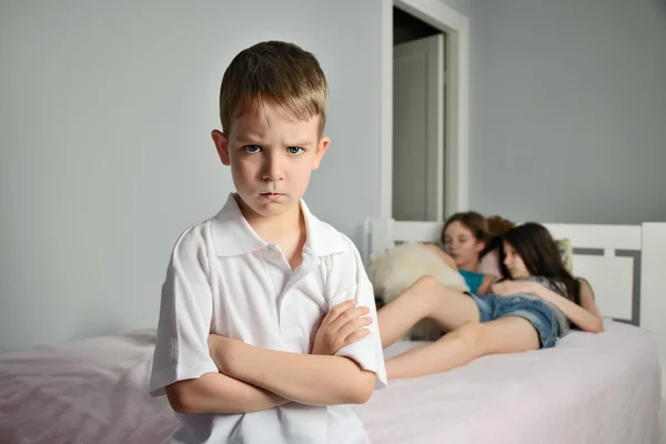 Angry boy with furrowed brows in the foreground in the room whit — Stock Photo, Image