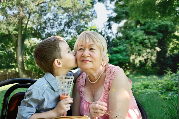 孙子拥抱和亲吻的脸颊，他的祖母。在中的眼泪 — 图库照片