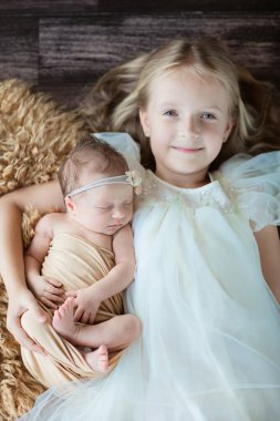 Küçük beyaz kız ve yeni doğmuş kız kardeşi. Küçük çocuk yeni kardeşle tanışıyor. Şirin bir kız ve yeni doğmuş bir bebek ev yatak odasında rahatlar. Evde iki çocuklu bir aile. Aşk, güven ve şefkat kavramı