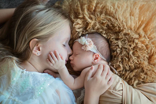 Klein blank meisje en haar pasgeboren zus. Een peuter die nieuwe broers en zussen ontmoet. Schattig meisje en pasgeboren baby ontspannen in een slaapkamer. Gezin met twee kinderen thuis. Liefde, vertrouwen en tederheid — Stockfoto