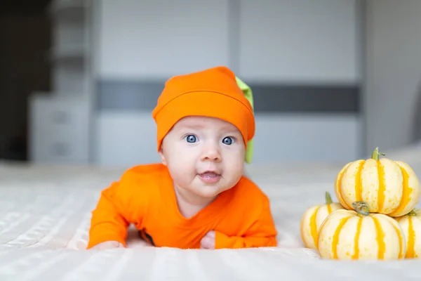 Vista de ângulo alto do bebê em traje de abóbora. Happy Kid dois meses de idade em laranja traje de Halloween na cama — Fotografia de Stock